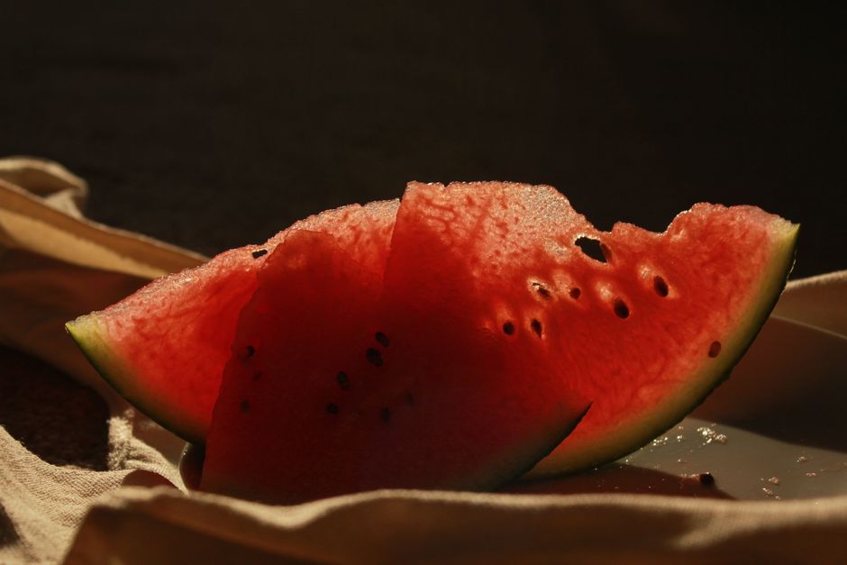 Close-up of fresh watermelon slices with seeds on a dark backdrop.