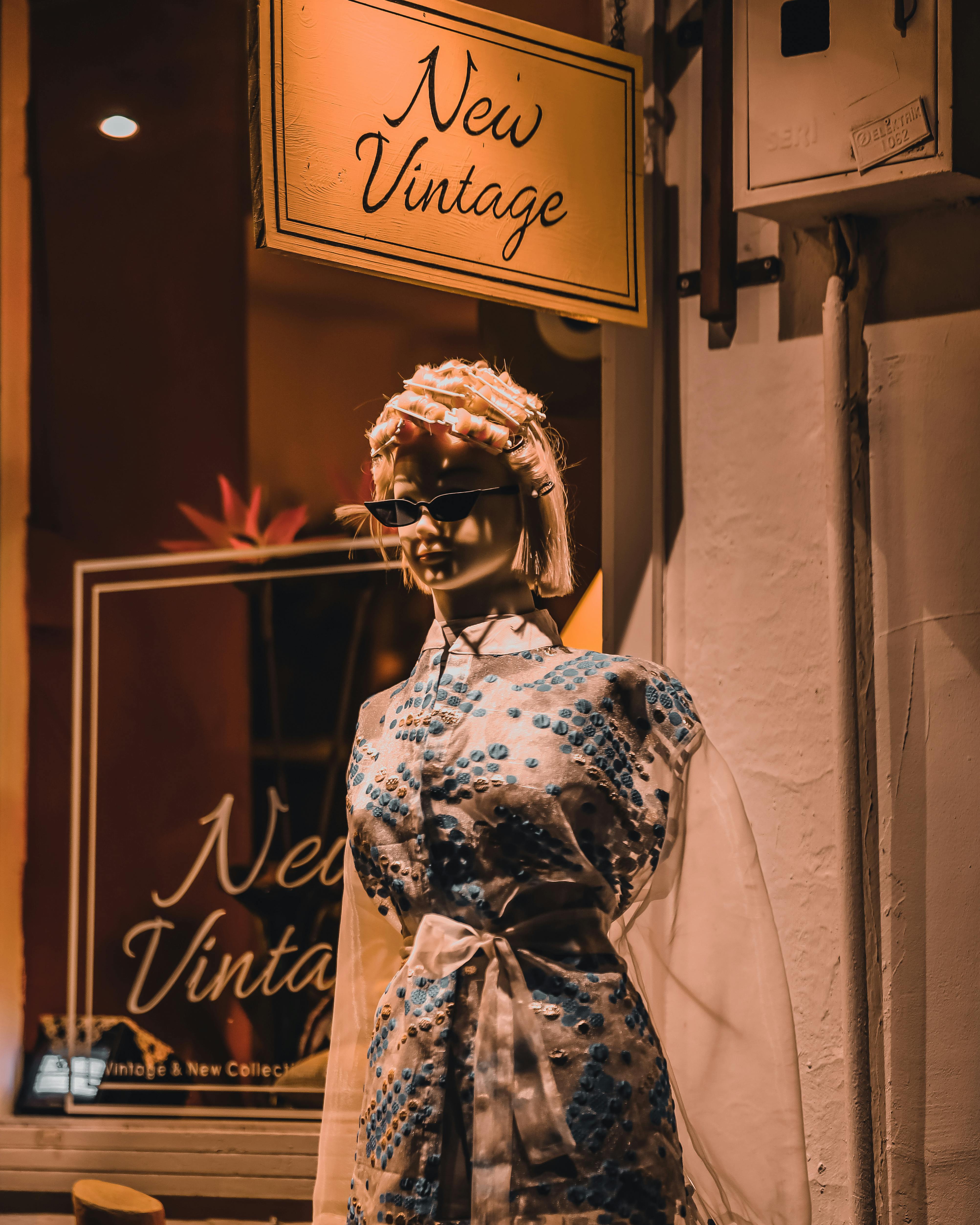 Stylish mannequin in a vintage clothes store showcasing retro fashion with sunglasses.