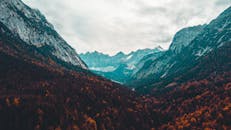 在这片宁静的山谷中，探索令人惊叹的秋色，并捕捉到戏剧性的多云天空