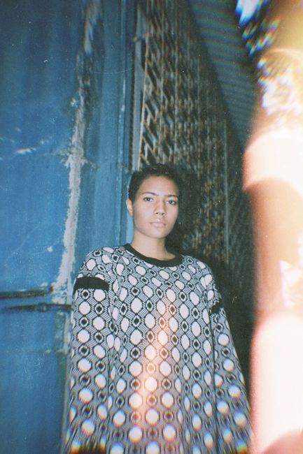 Vintage-style portrait of a woman indoors wearing a geometric sweater with soft light.