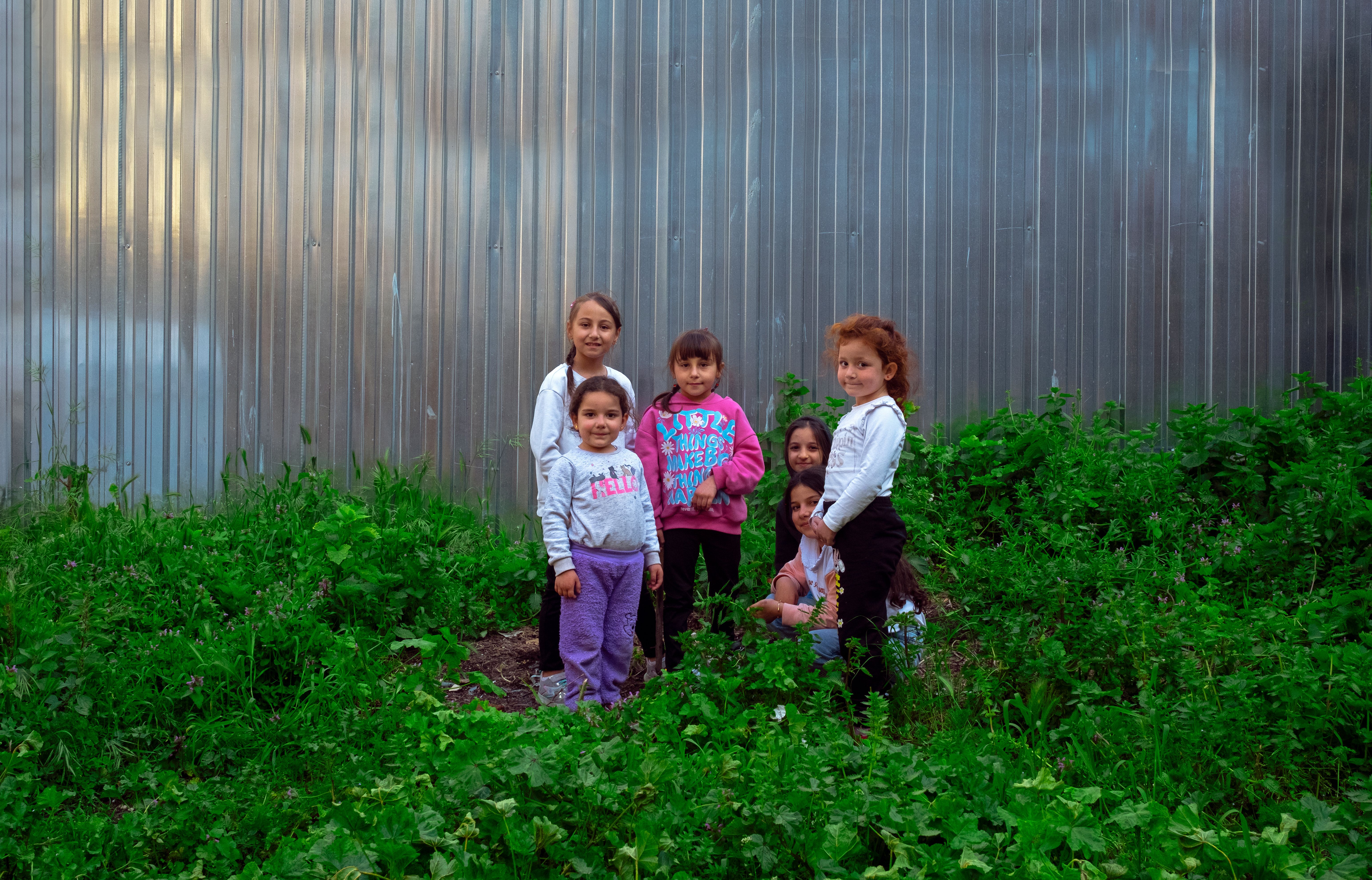 Group of children smiling and playing near a metal wall in Istanbul.