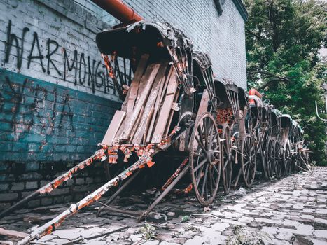 Old wooden rickshaws lined in a cobblestone alley in Kolkata, India, depicting urban decay.