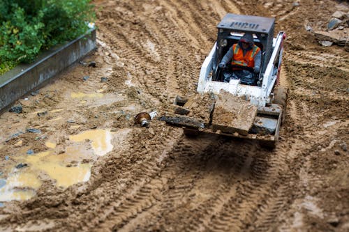 Man Driving a Backhoe on a Construction Site 