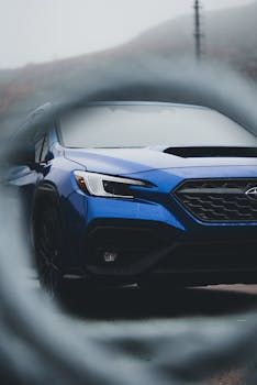A vibrant blue sports car captured through an artistic blur effect on a misty day.