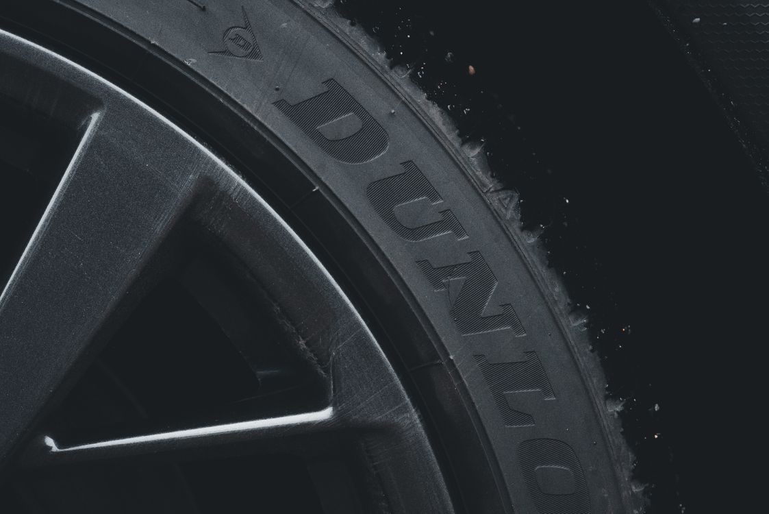 Free Detailed close-up of a Dunlop tire and rim showcasing its texture and brand text. Stock Photo