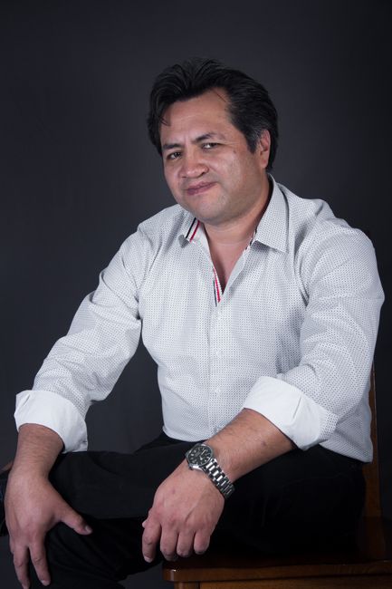 Portrait of a confident man in a white shirt posing in a studio setting with a neutral background. - The Role of Professional Photos on CVs: Regional Norms, Biases, and Global Best Practices