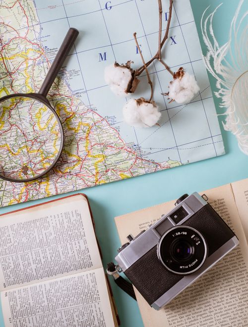 Free Flat lay of a camera, map, and magnifying glass with cotton sprigs for travel planning. Stock Photo