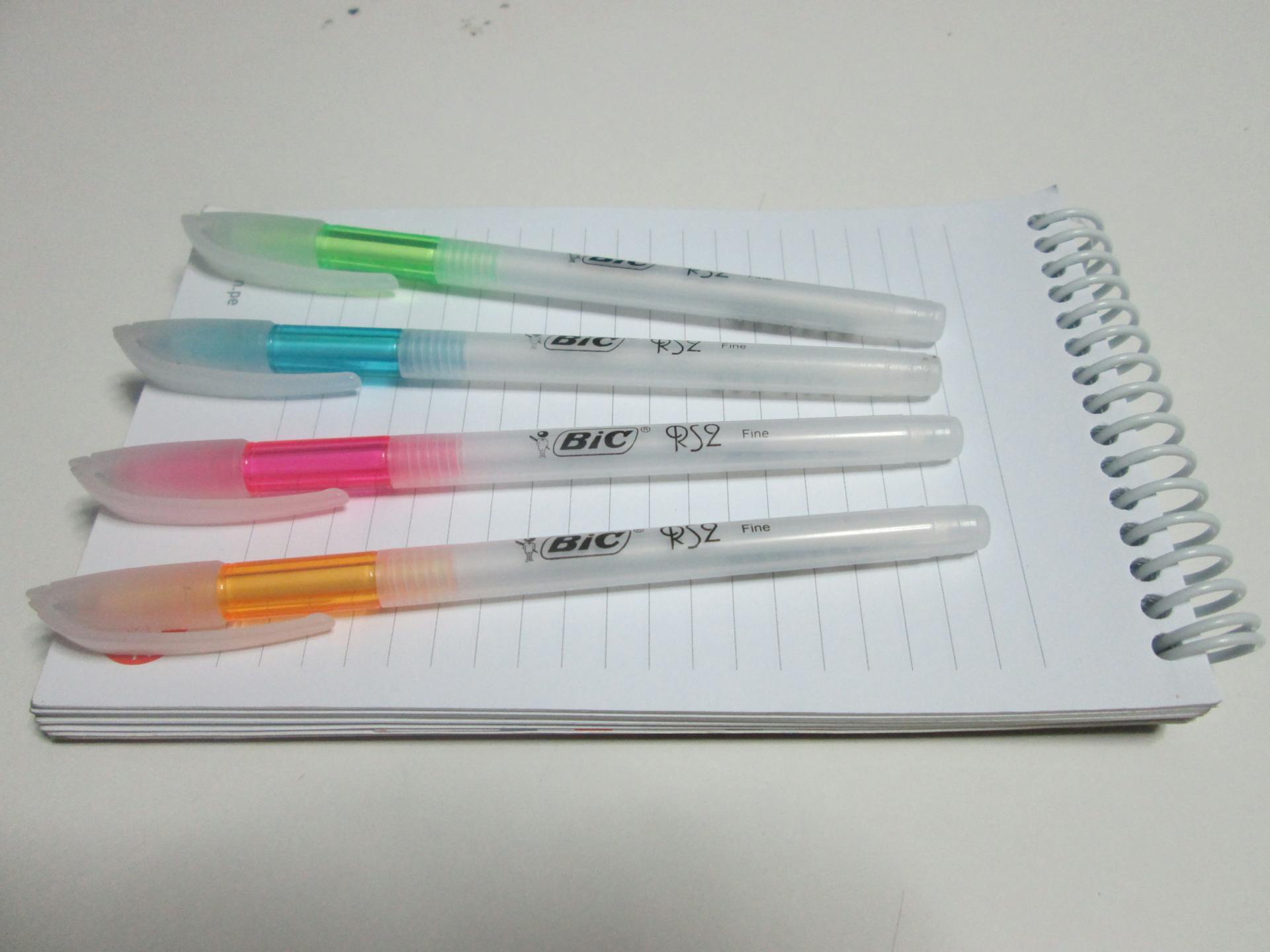 Four colorful Bic pens arranged on a spiral notepad, showcasing vibrant organization.