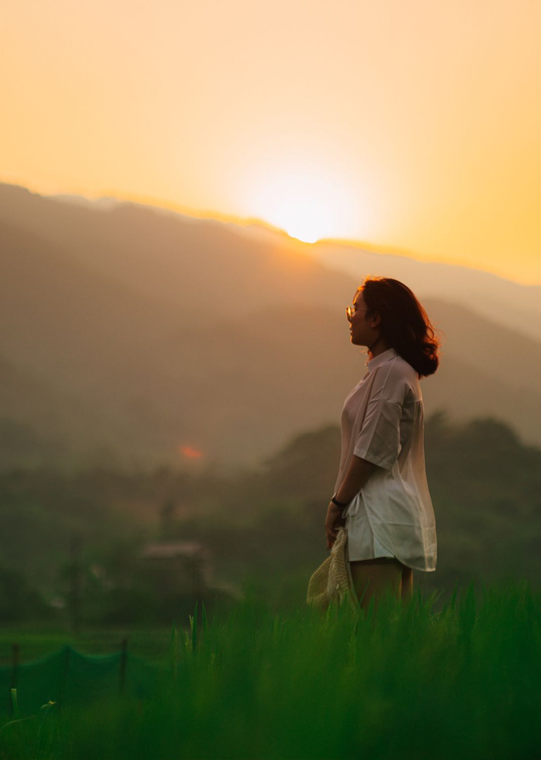 Scenic Photo of a Woman Standing in a Field at Sunset · Free Stock Photo