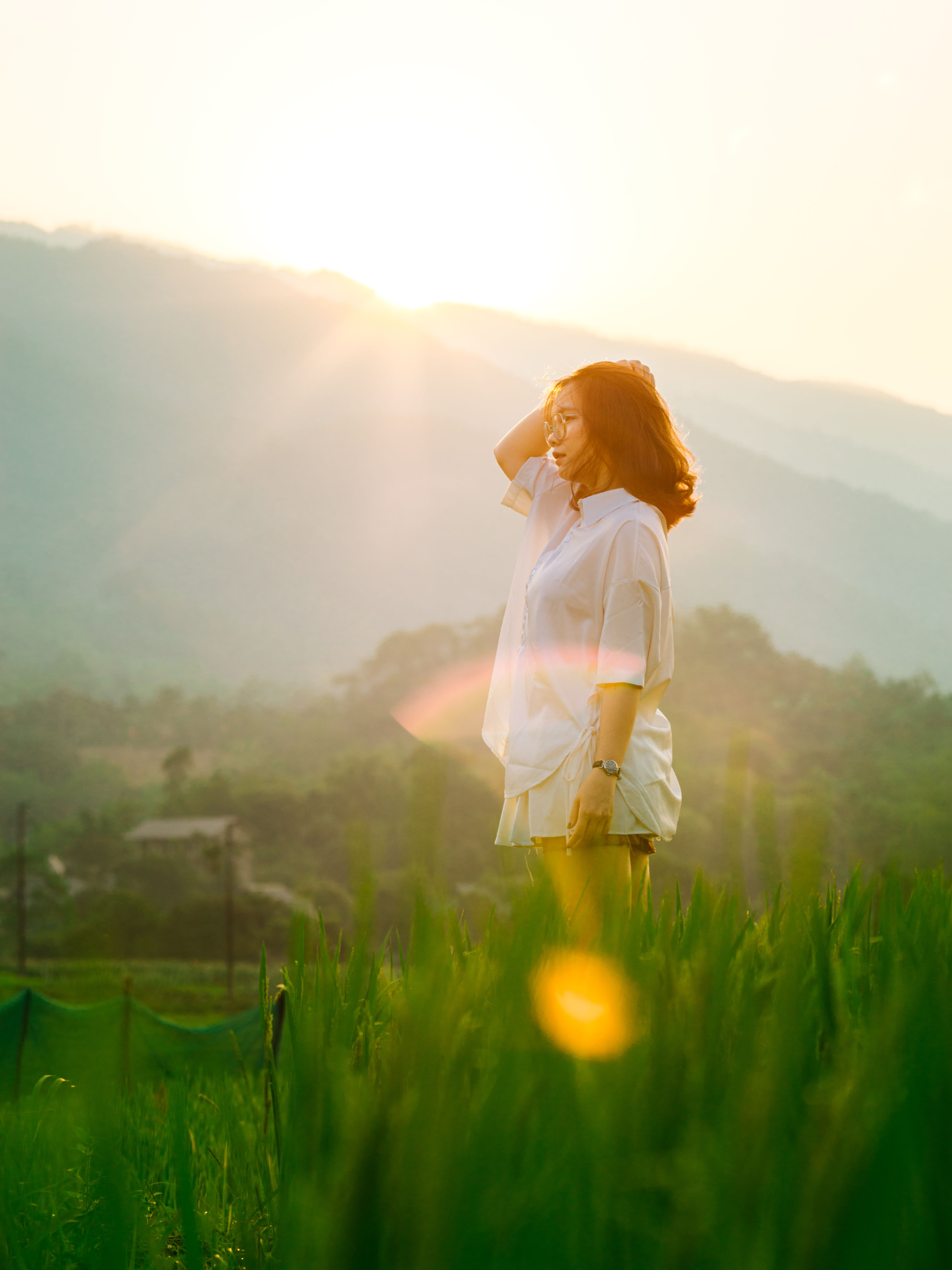 Woman Standing in Grass Field at Sunset · Free Stock Photo