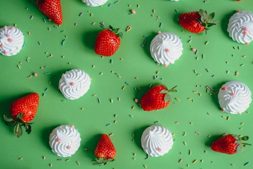 Meringues and Strawberries Lying on Green Back