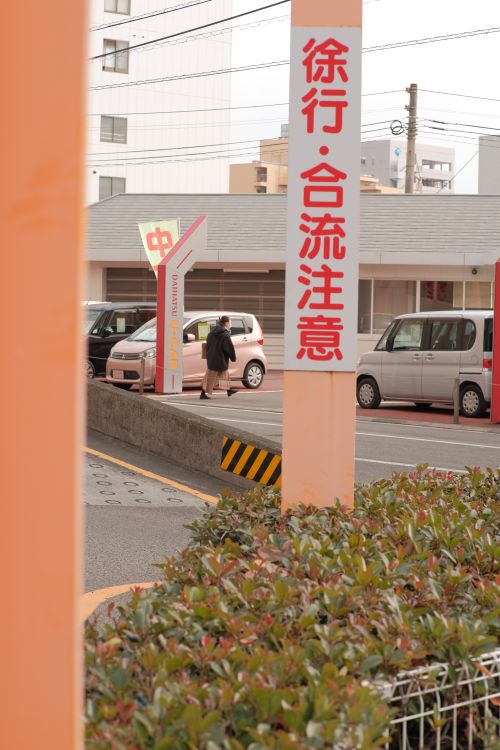 Free Street view featuring Japanese road signs, parked cars, and greenery. Stock Photo