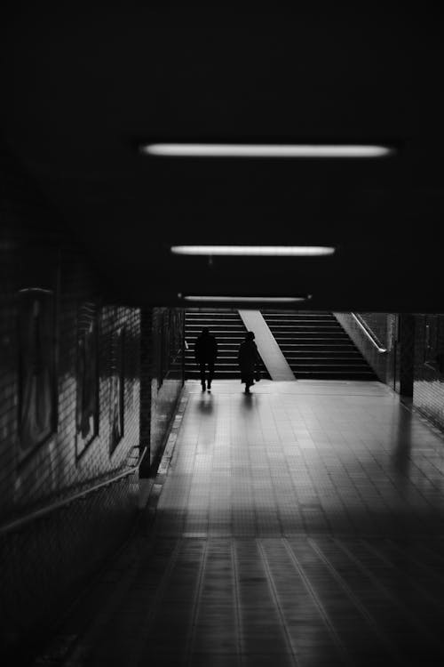 Black and White Photo of People Walking through Underwater Tunnel