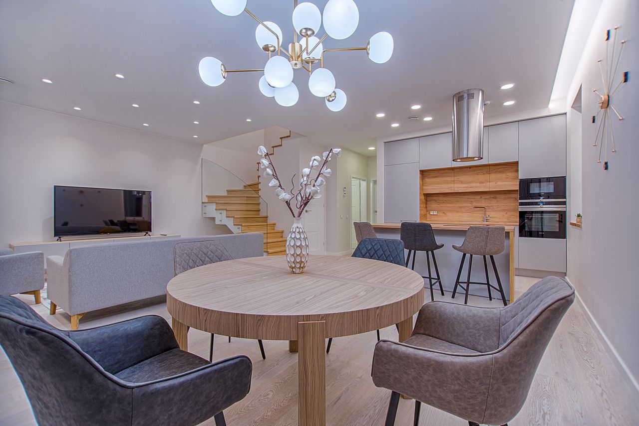 Mixed upholstered dining chairs in gray, navy, and taupe around a round light-wood table