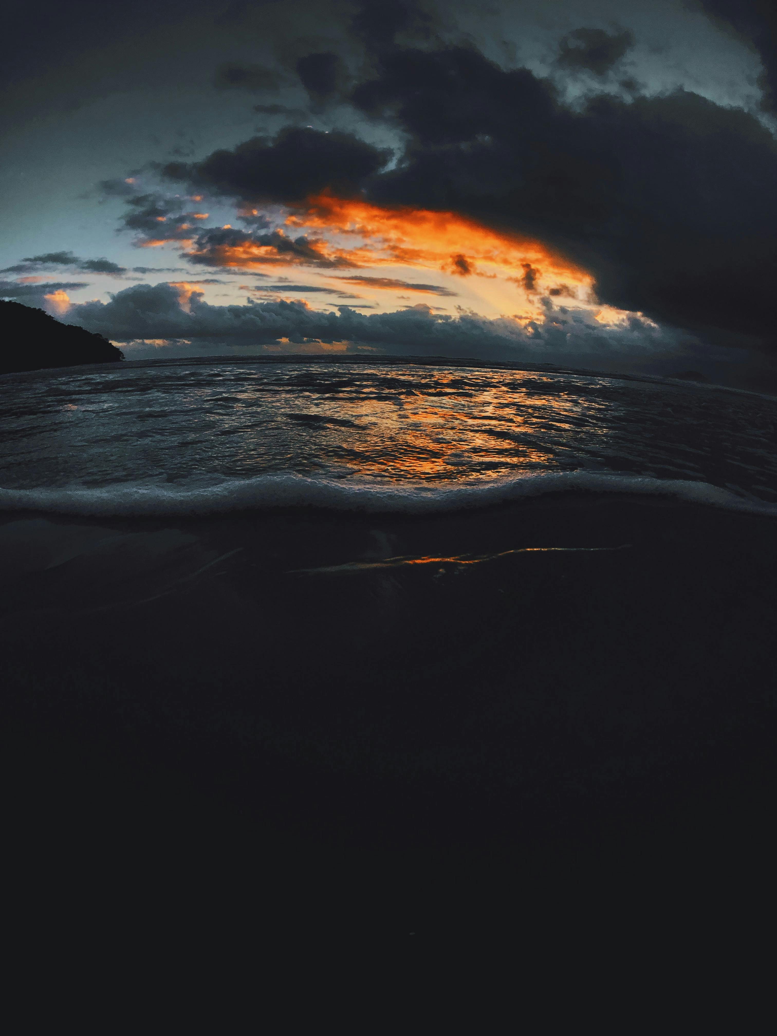 乌云缭绕的天空下，海浪之上，日落景象令人惊叹