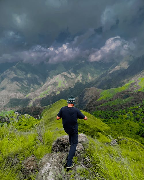 High Angle Shot of a Man Standing on a Mountain Peak 