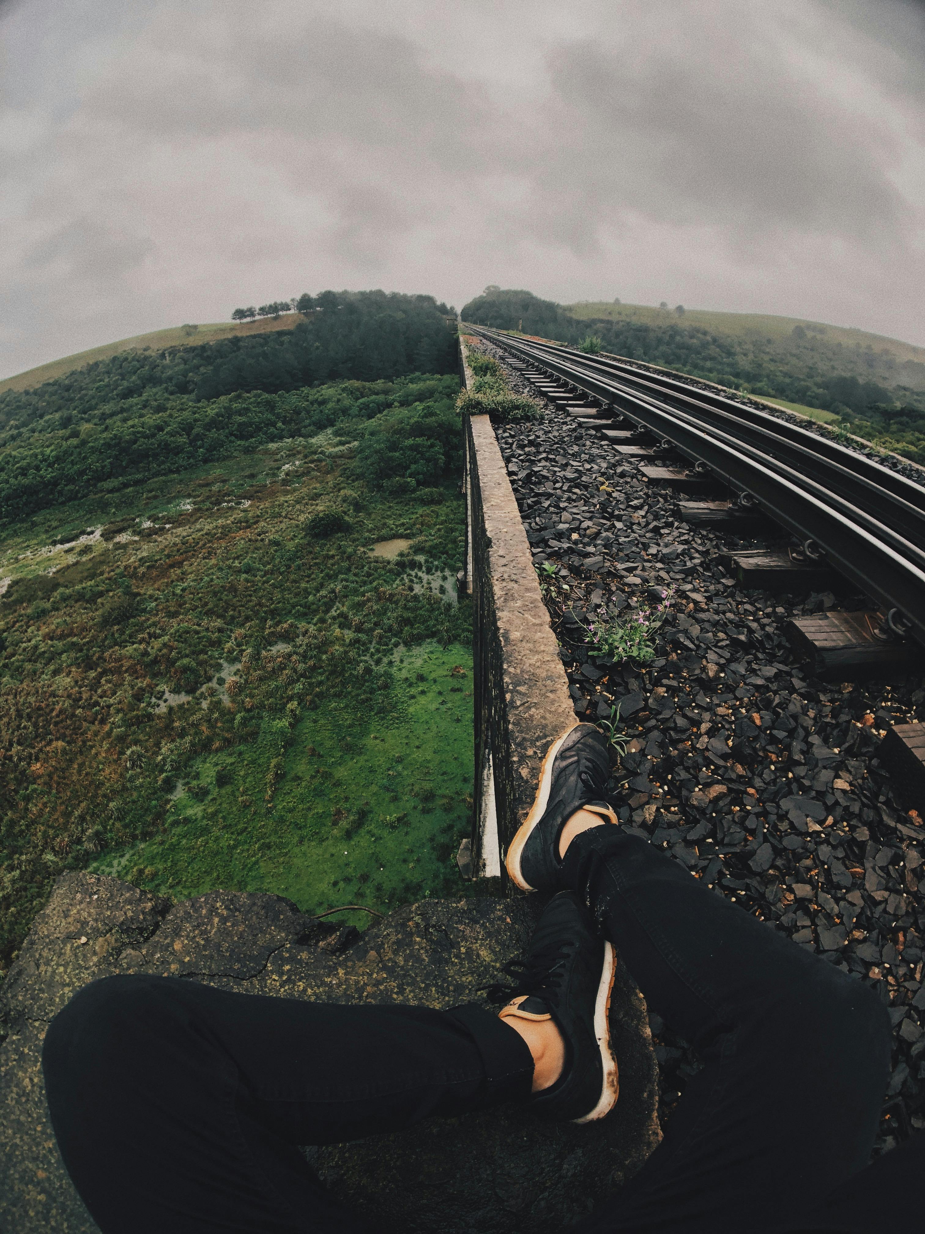 一个人坐在郁郁葱葱的铁路桥上，捕捉自然与冒险