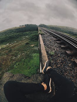 一个人坐在郁郁葱葱的铁路桥上，捕捉自然与冒险