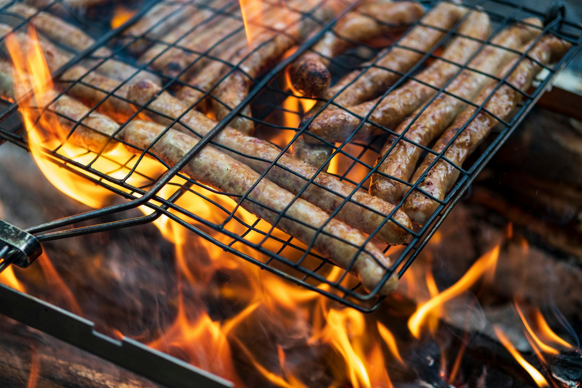 BBQ in the garden. Grilling sausages on barbecue grill.  Bavarian sausages. Barbecue cooking. Cooking food on an open fire.