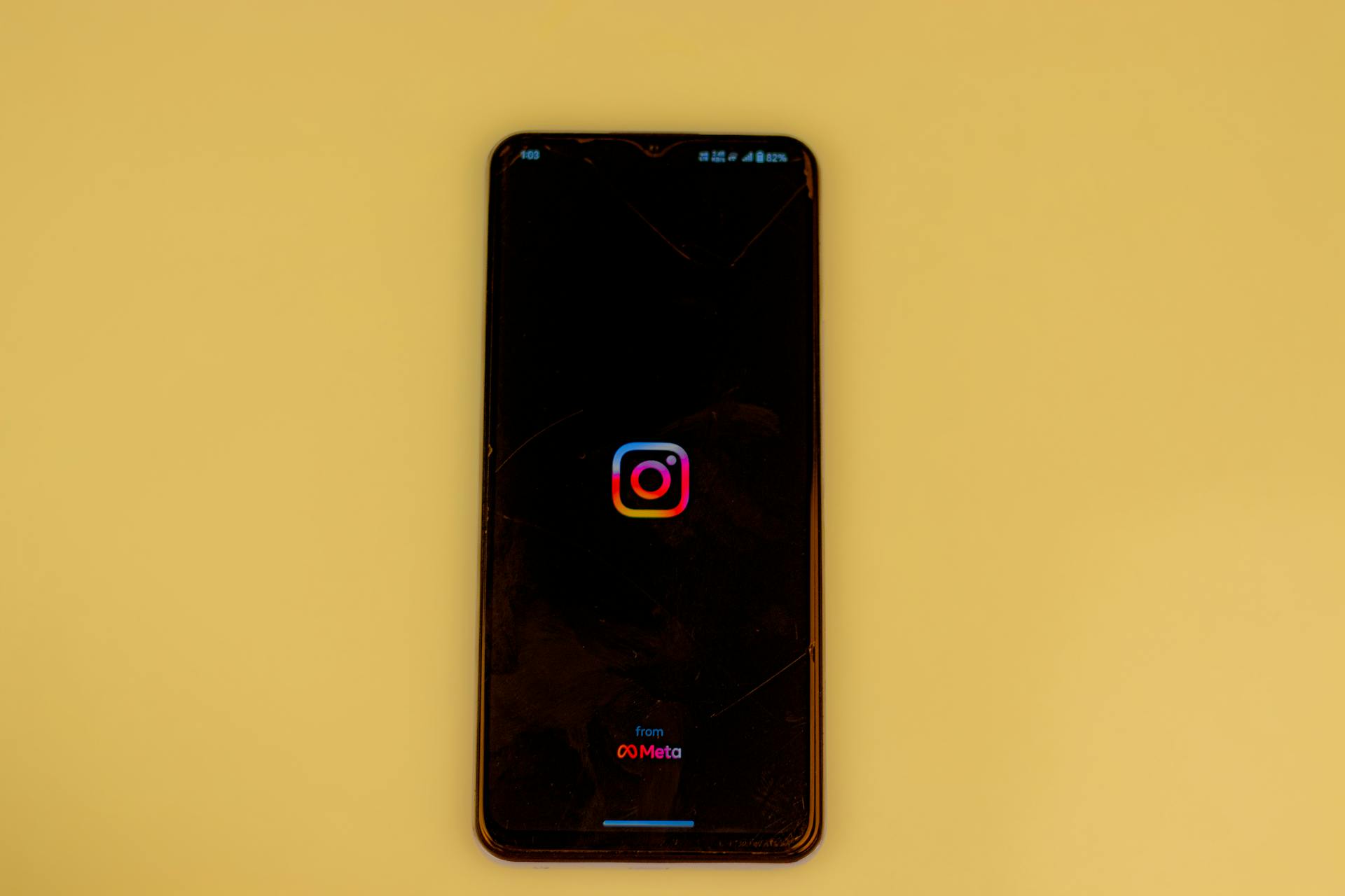 A smartphone displays the Instagram logo on a vibrant yellow background, emphasizing modern social media themes.