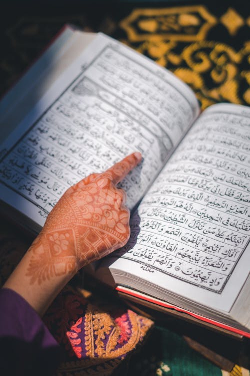 Henna Tattoo on Woman Hand over Koran