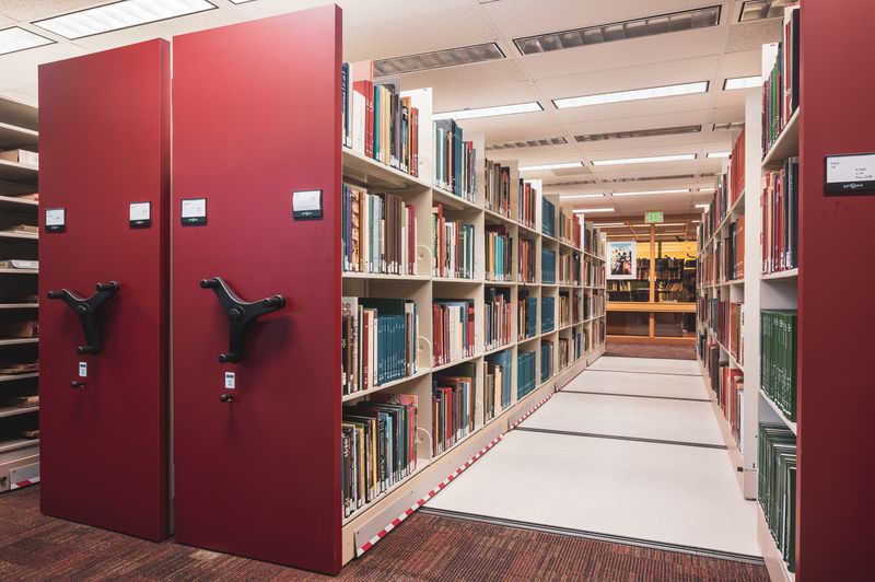 Long library aisle lined with mobile shelving units full of reference books