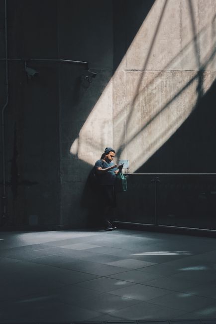 Person reading a book in a sunlit industrial space, creating a dramatic urban scene.