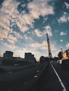 黄昏时分，城市景观以多云天空为特色，街道两旁排列着汽车