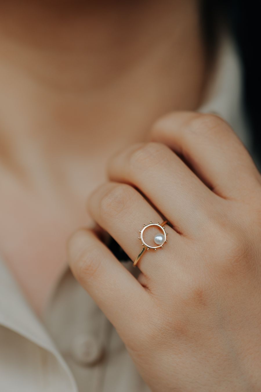 Pearl gold ring held in soft light