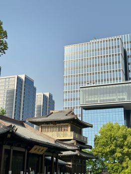 Contemporary skyscrapers loom over a classic Chinese temple, showcasing urban architectural contrast.
