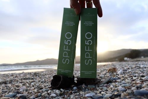 Free Packaging with Sunscreen on the Ground on the Beach  Stock Photo