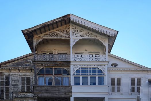 A detailed view of a half-renovated wooden house facade, showing old vs new.