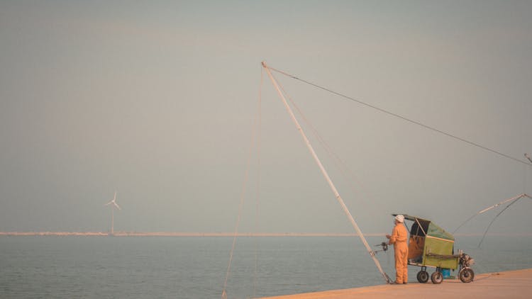 Man Lowering A Pole Into The Sea