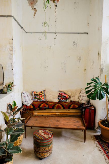Inviting bohemian lounge featuring rustic furniture and lush plants in a serene indoor setting.
