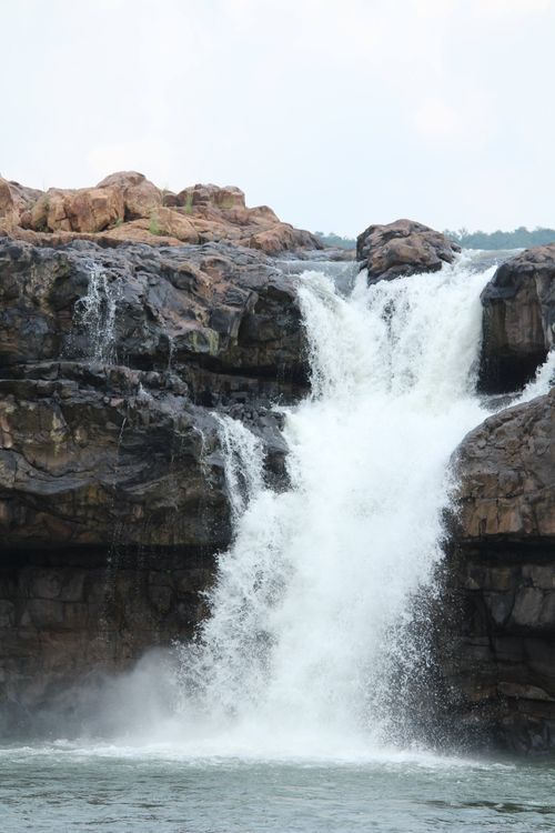 Free A powerful waterfall cascades down rocky cliffs, capturing the essence of nature's beauty and force. Stock Photo