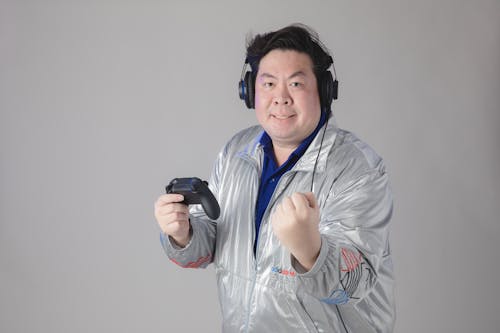Imagen gratuita de un hombre con una chaqueta plateada sosteniendo un controlador de videojuegos
