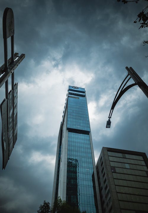 Low Angle Shot of a Modern Skyscraper under a Cloudy Sky 