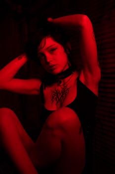 Artistic portrait of a woman with tattoos in dramatic red lighting.