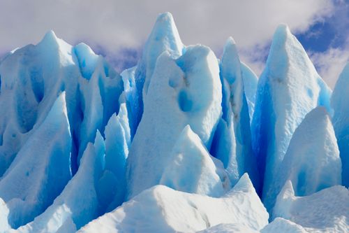 Free Breathtaking view of sharp, blue ice formations against a cloudy sky in a polar environment. Stock Photo