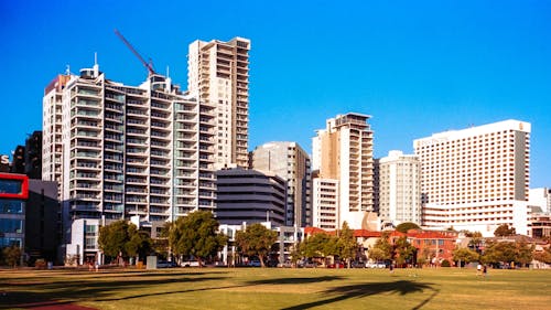 A large grassy area with tall buildings in the background
