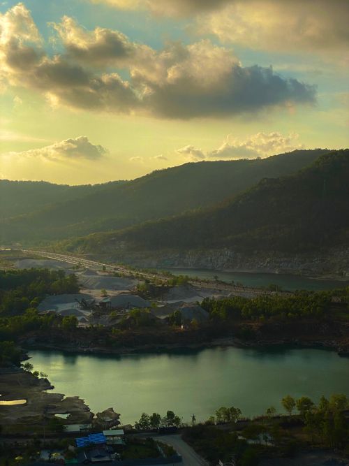 Free Tranquil lake surrounded by rolling hills and mountains at sunrise, offering a peaceful natural landscape. Stock Photo