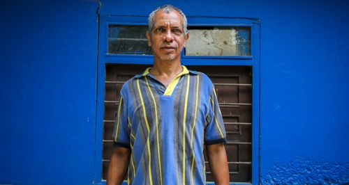Free Casual portrait of a senior man standing against a vivid blue wall. Stock Photo