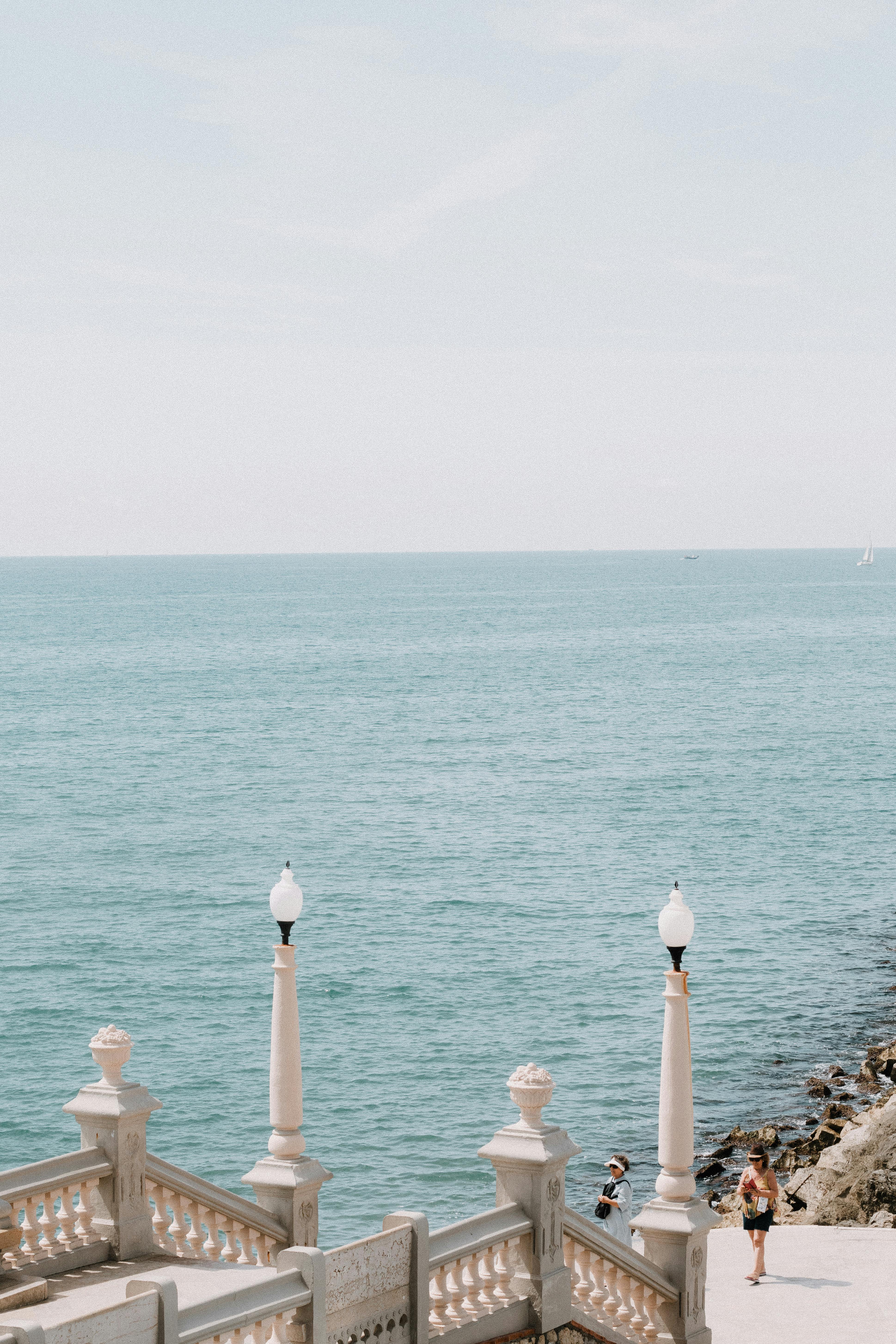 Bright seaside view from Sitges promenade with ornate lamps and clear blue sea.