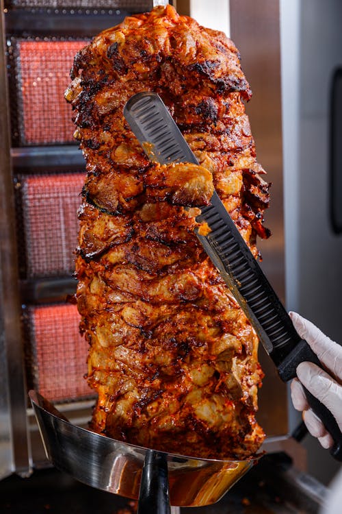 Cook Cutting Meat on a Rotating Spit to Prepare Shawarma