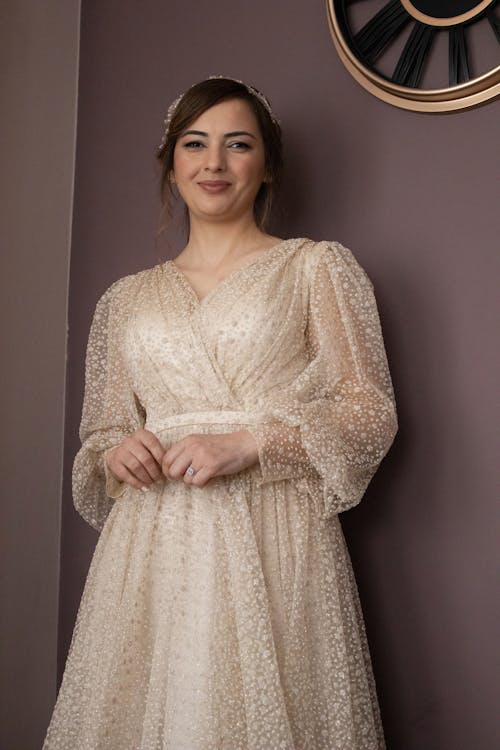 Beautiful Young Woman in White Wedding Dress Posing by a Pink Wall