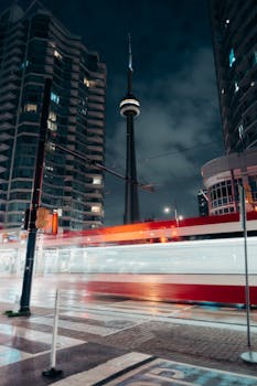 Toronto's CN Tower and cityscape illuminated at night with dynamic streetcar light trails.