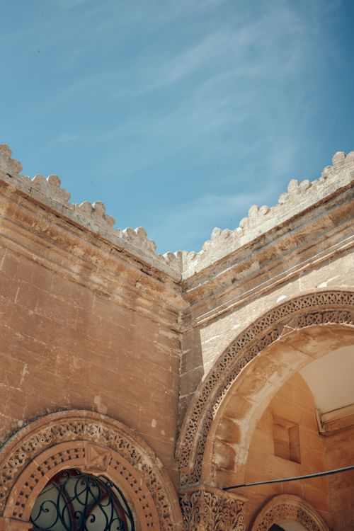 Free Close-up of an intricately ornamented stone building facade with arches against a clear blue sky. Stock Photo
