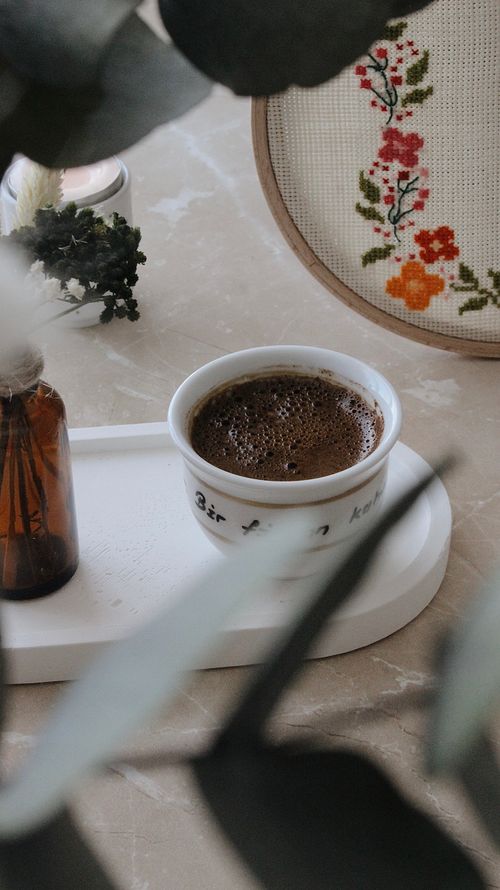 Free Warm high-angle view of a coffee cup with embroidery art in the background. Stock Photo