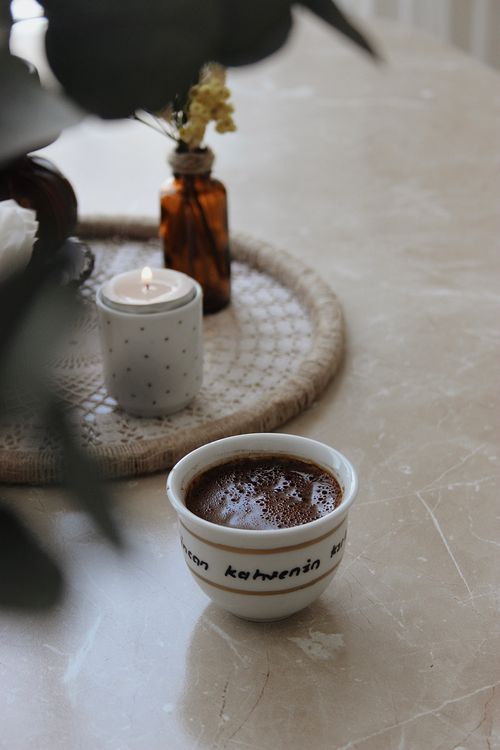 Free A steaming coffee cup on a marble table with a lit candle and decorative items, creating a warm and inviting ambiance. Stock Photo