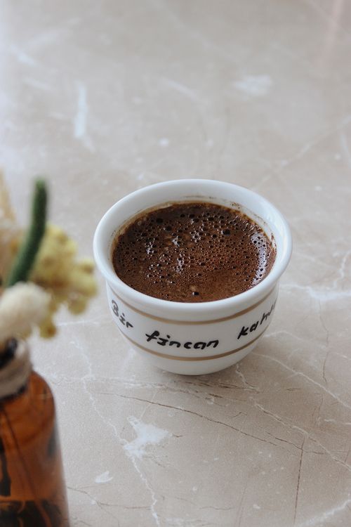 Free A close-up shot of a Turkish coffee cup on a marble table with floral decor. Stock Photo